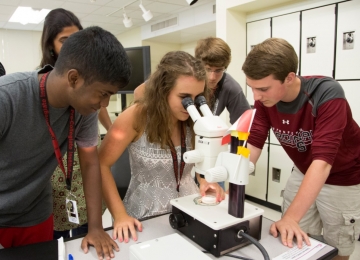 Students in Stanford Pre-Collegiate Studies program looking into a microscope Students in Stanford Pre-Collegiate Studies program looking into a microscope